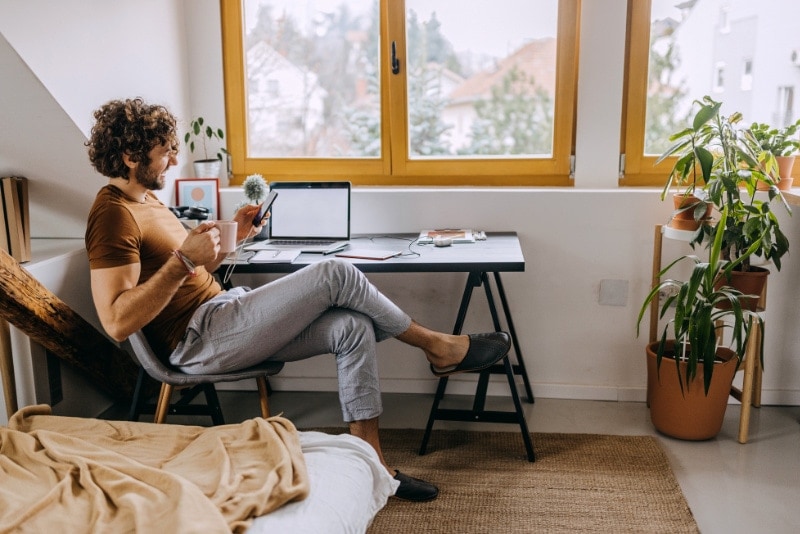 Young handsome man makes business in the web at home.