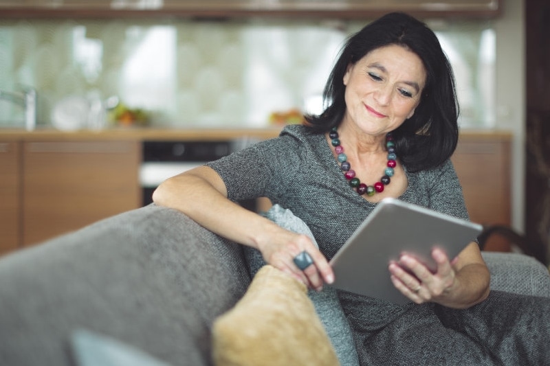 woman smiling on couch with ipad